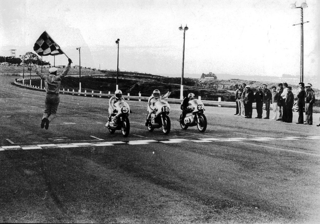 A celebre bandeirada de Eloi Gogliano para a chegada de Walter Tucano Barchi, Denísio Casarini e Paolo Tognocchi. Foto mês Dezembro: Edson Lobo / Motostory 