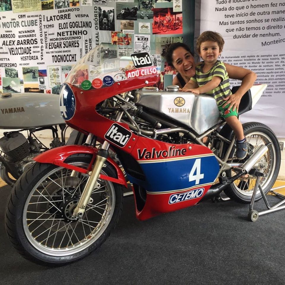 Gabi Neves, filha de Adu Celso, com o filho João, neto do nosso campeão, admirando a moto com a qual Adu brilhou nas pistas. Foto Acervo pessoal.