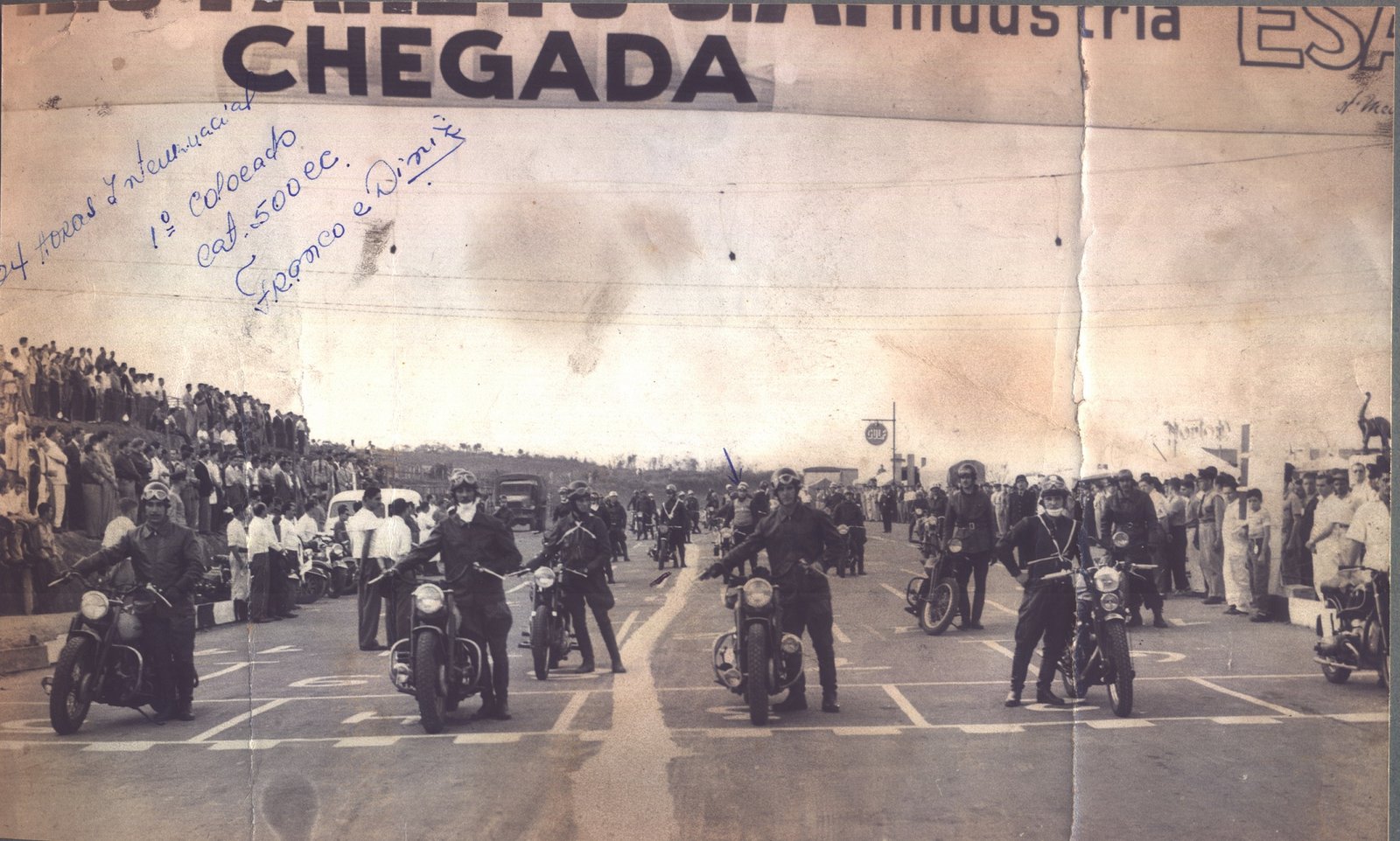 Foto largada das 24hs de Interlagos de 1952 – Franco Bezzi aparece ao fundo, marcado com a seta azul e Edgard Soares aparece na primeira fila – na direita a BMW R68 da dupla vencedora Caio Marcondes e Edward Pacheco – Acervo Família Bezzi / Motostory